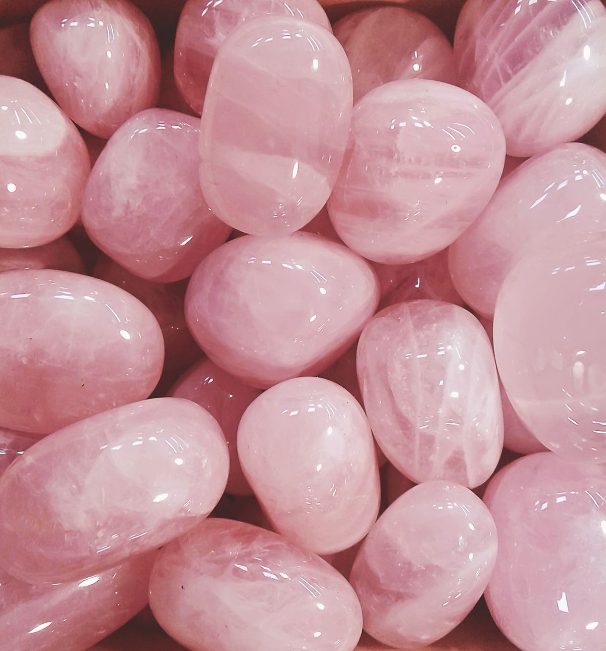 Pile of pink rose quartz. Polished and shiny oval gemstones.