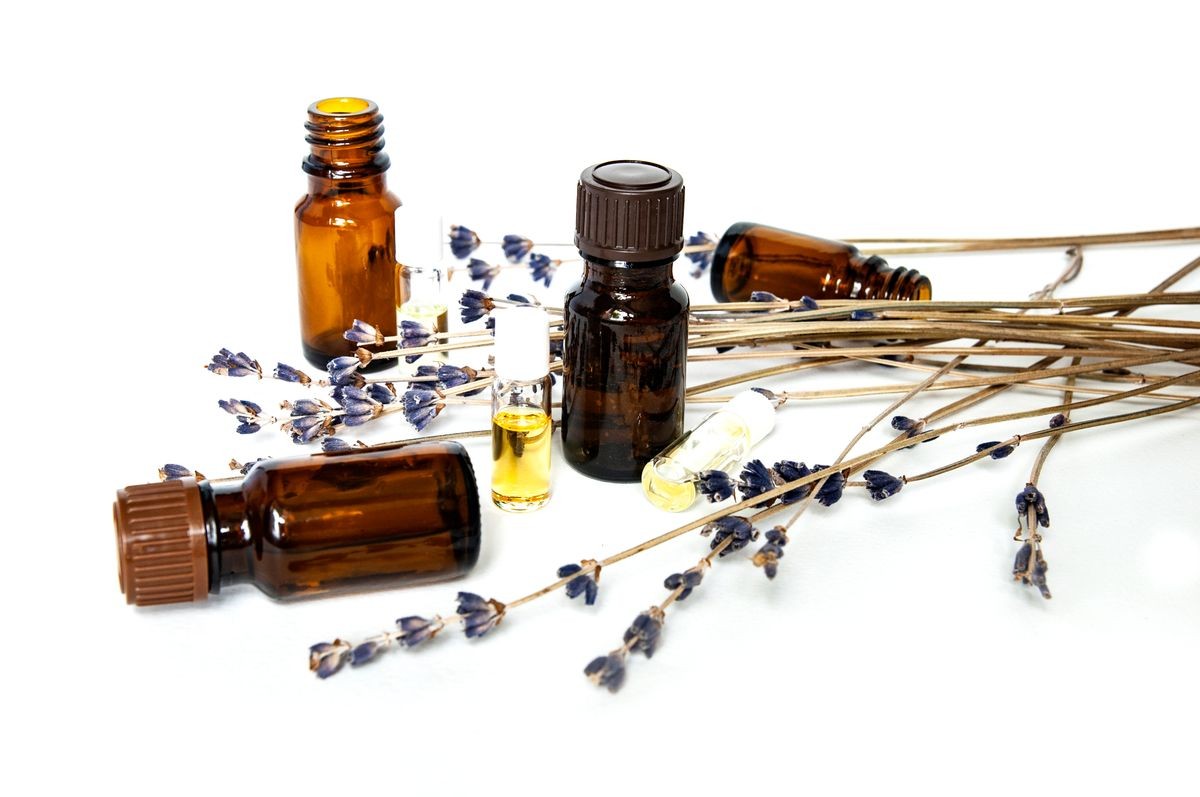 Selection of essential oils, with herbs on white background. Brown and transparent Bottles 