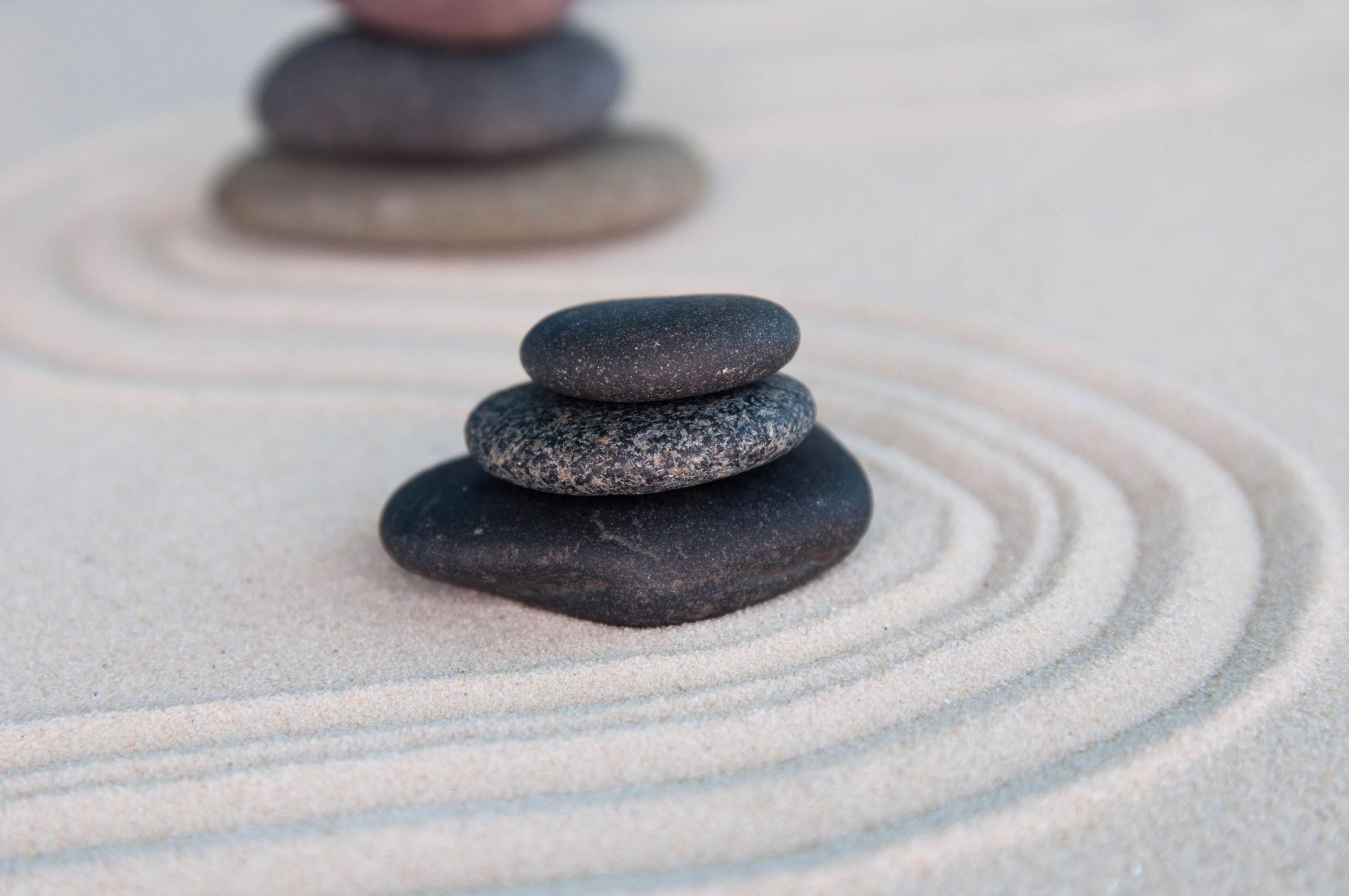 Pyramids of gray zen stones on light sand. Concept of harmony, balance and meditation, spa, massage, relax